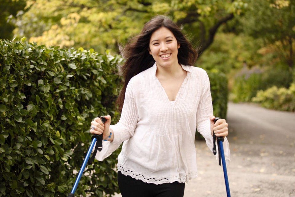 Xian smiling at the camera standing in a white blouse with her ski poles.

