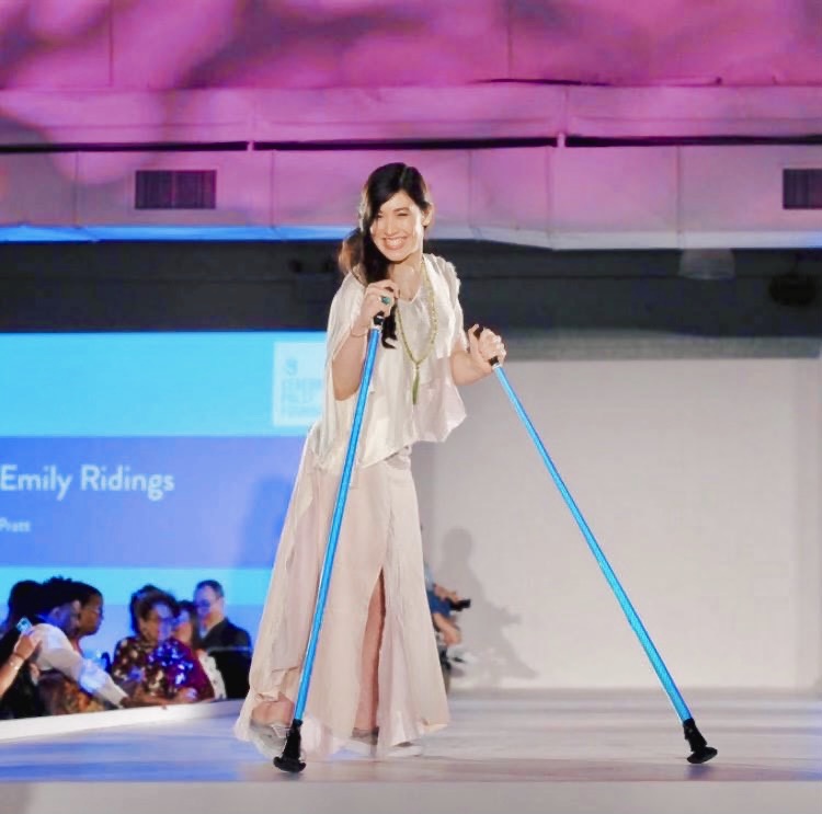 Xian turned toward the camera smiling standing on the runway in a sustainable silk top and tencel skirt, holding her iridescent ski poles.